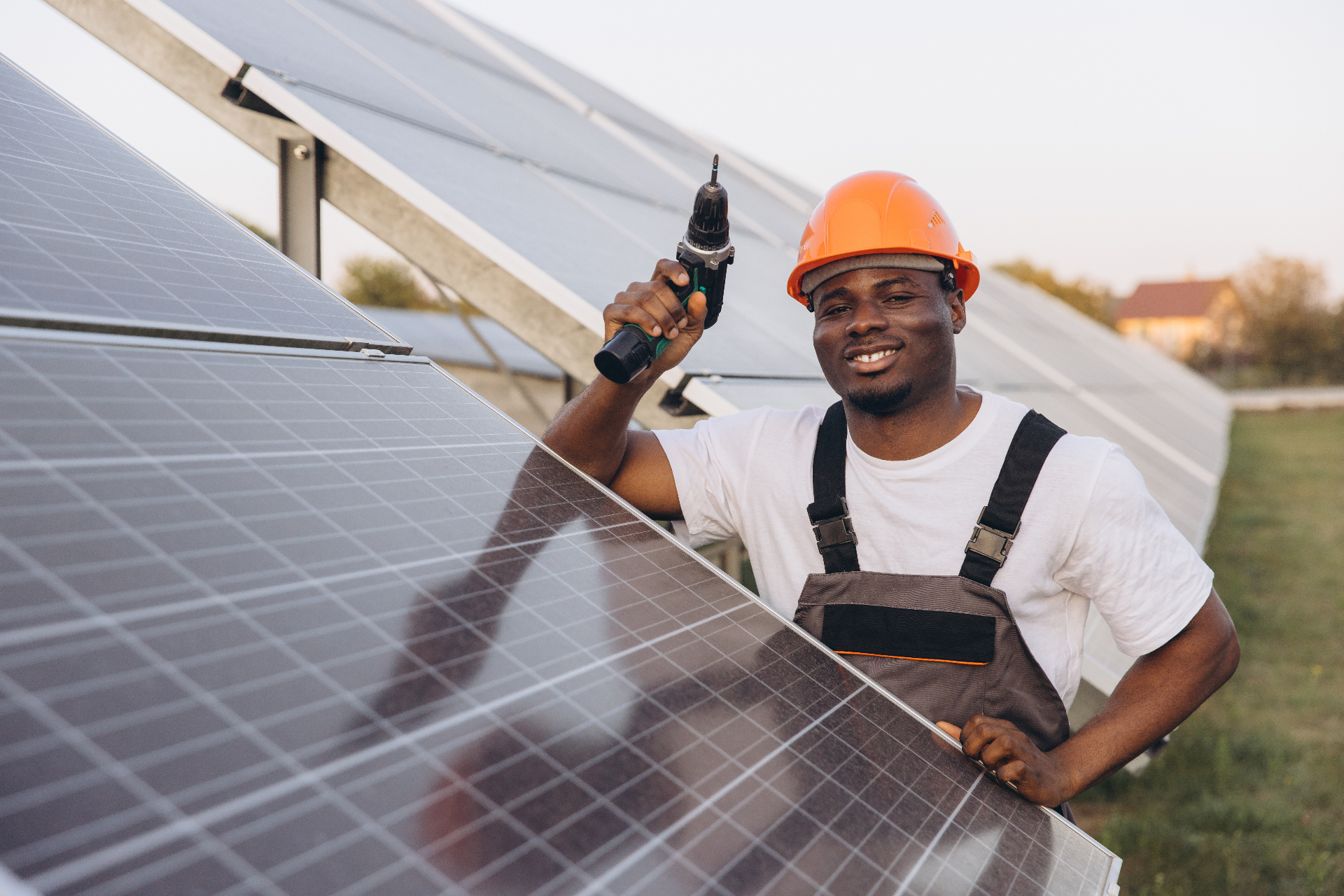 Agetech Power technician in a hardhat holding a drill beside a solar panel