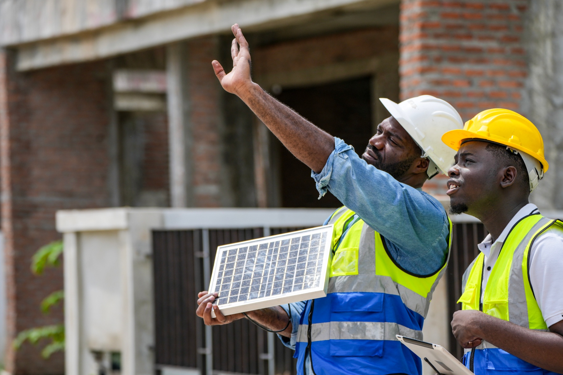 Two engineers in high-visibility vests inspecting a photovoltaic panel on site